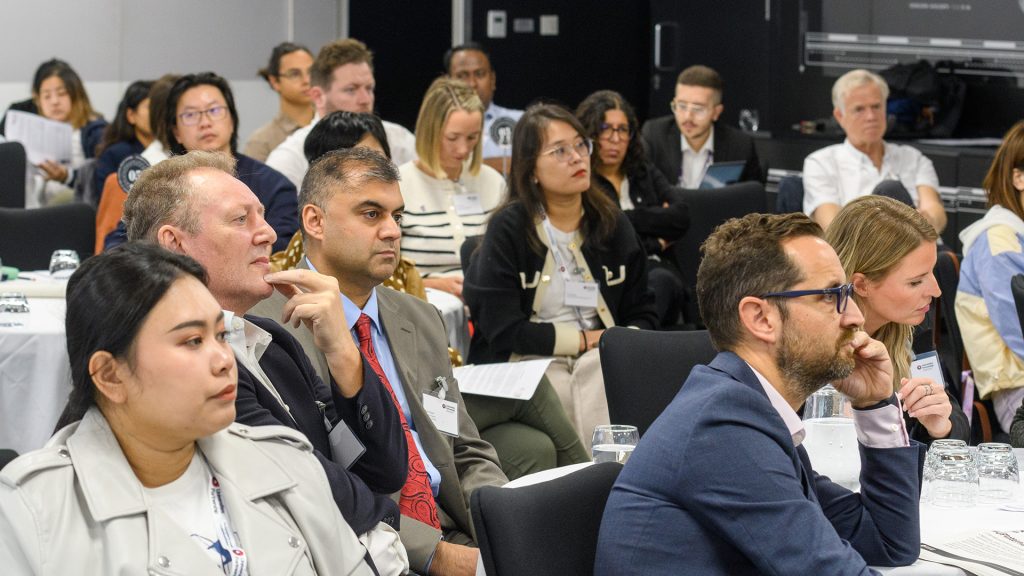 A group of students, professionals and partners are listening to a presentation